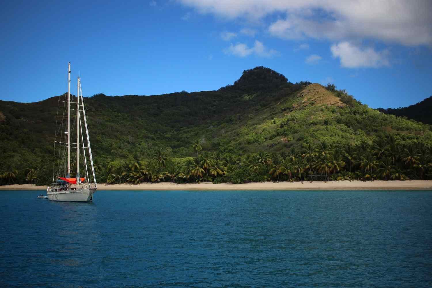 Scenic St. Lucia beach with turquoise Caribbean water, a sailboat, and lush green mountains