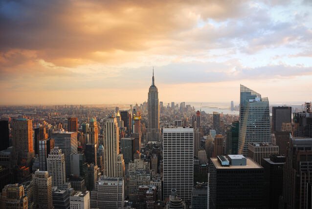New York City skyline at sunset featuring the Empire State Building and surrounding skyscrapers.