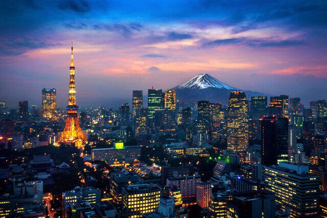 Tokyo skyline at dusk with the illuminated Tokyo Tower, city lights, and Mount Fuji in the distance.