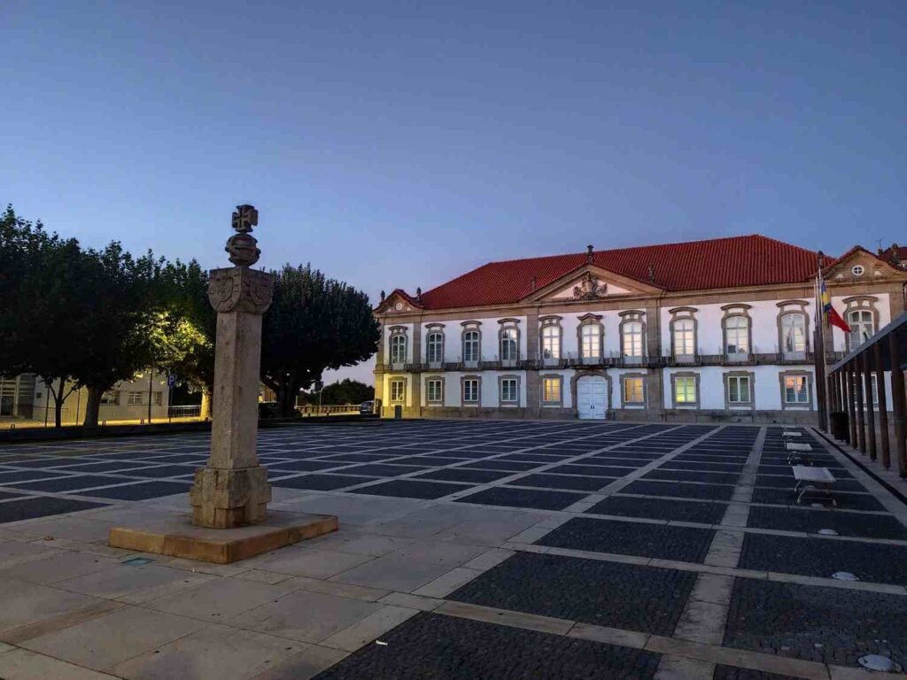 Historic square with traditional Portuguese architecture and a stone monument at dusk