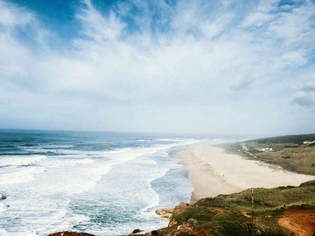 Wide sandy beach and Atlantic Ocean coastline in Nazare Portugal
