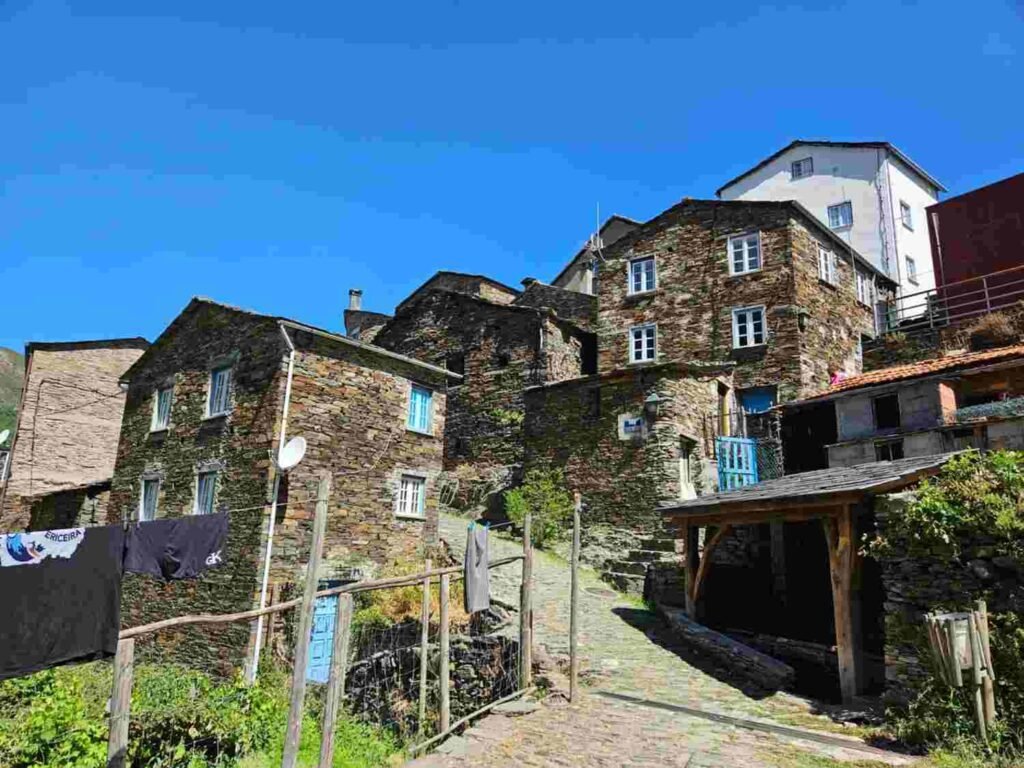 Stone buildings and blue doors along a narrow lane in a Portuguese hillside village
