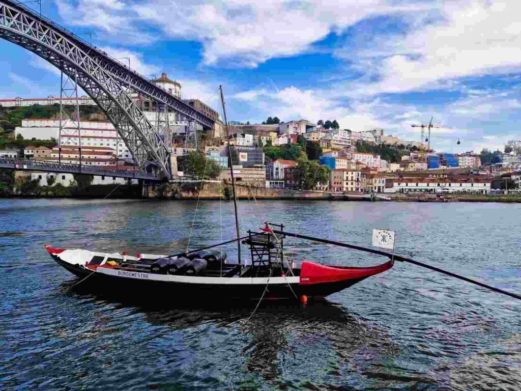 Traditional rabelo boat on the Douro River beneath the Dom Luis I Bridge in Porto Portugal