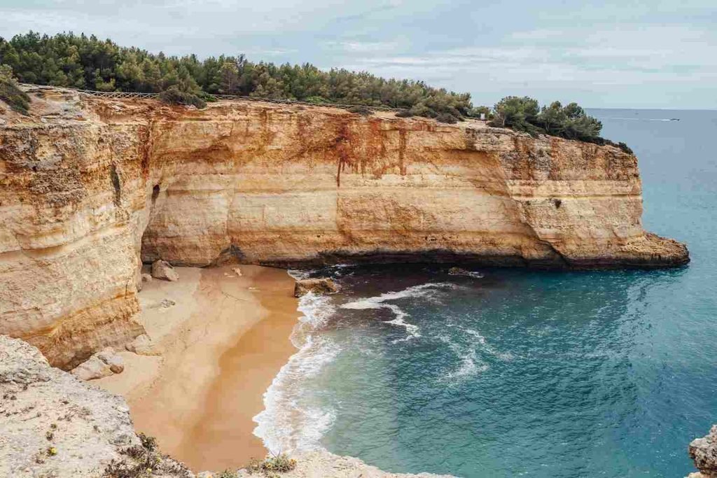 Long sandy shoreline beneath golden cliffs at Praia da Falésia, Algarve