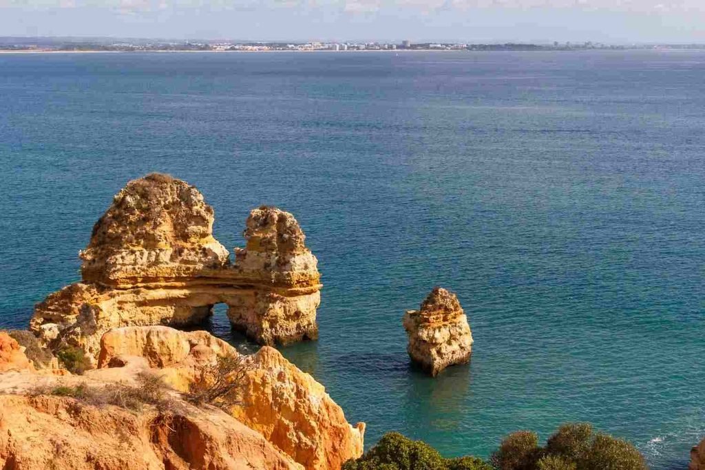 Small sandy cove surrounded by tall golden cliffs at Praia do Camilo, Lagos