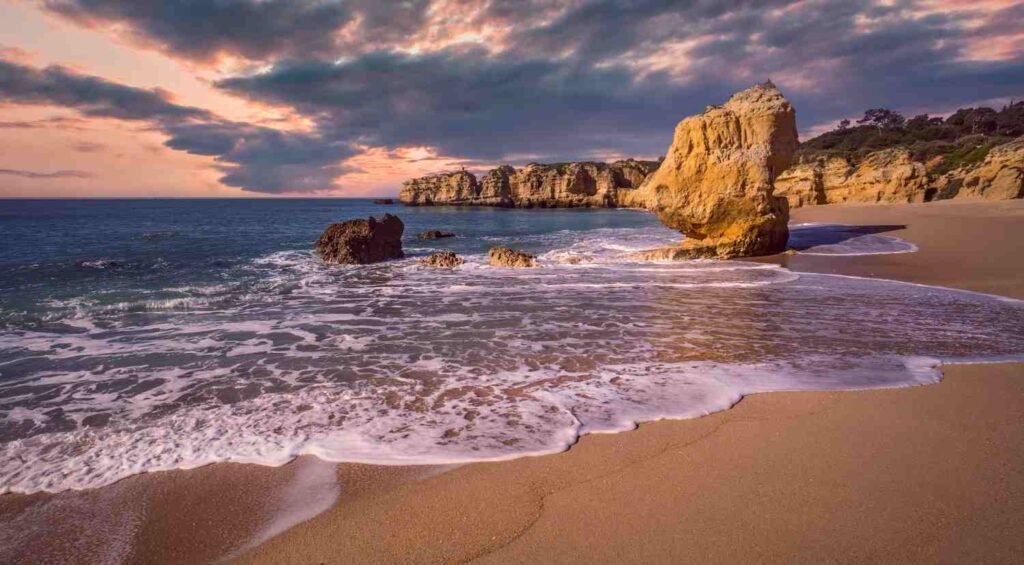 Golden sea cliffs and sandy beach along the Algarve coast in Portugal