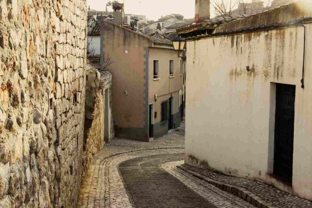 Narrow cobblestone street between historic stone and whitewashed houses in Obidos Portugal